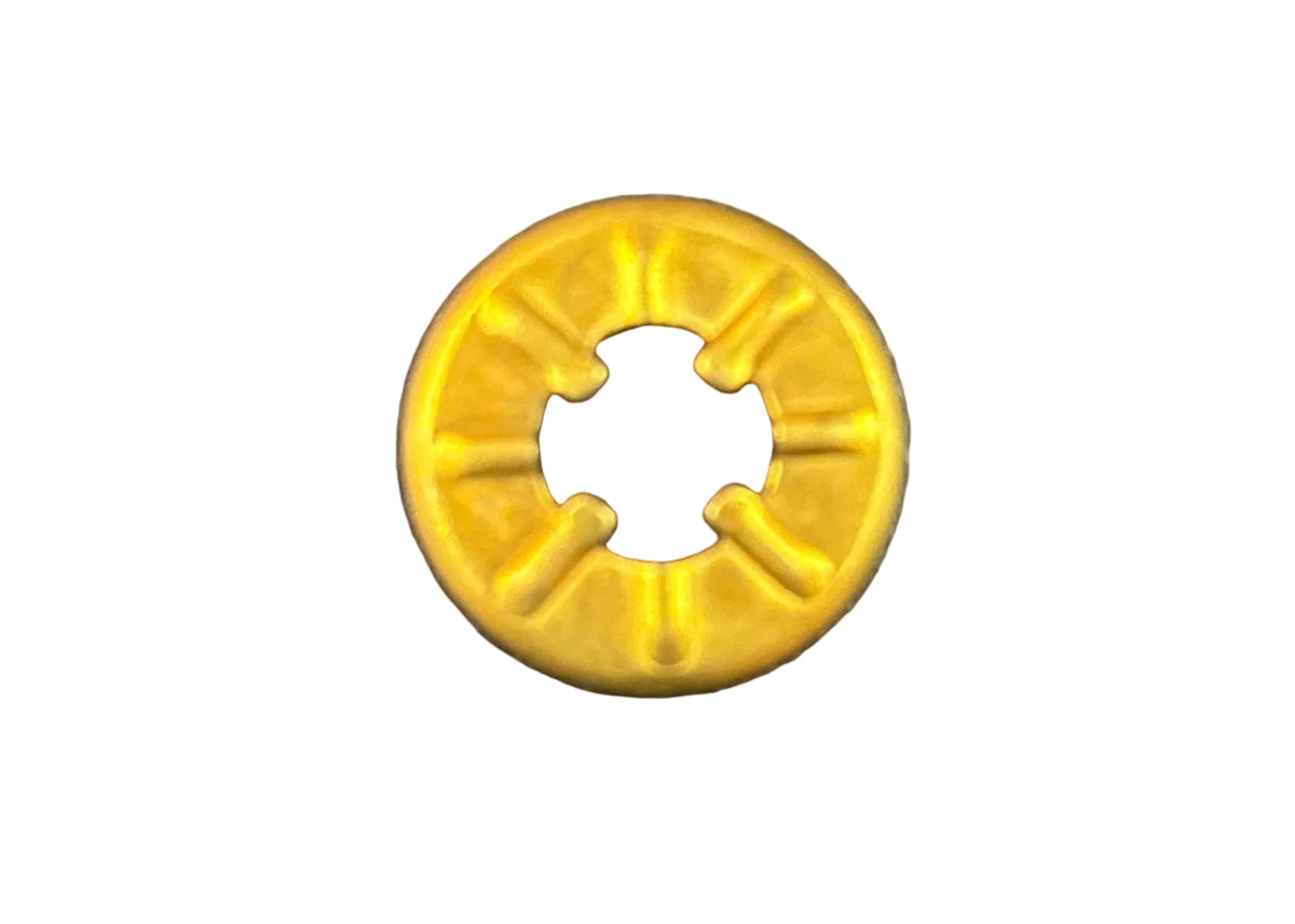 A small yellow plastic ring-shaped fastener or grommet with a cross-shaped hole in the center, placed on a dark textured surface.