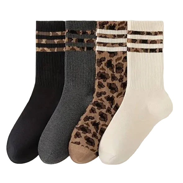 Four pairs of socks in black, gray, leopard print, and white with striped cuffs on a light background.